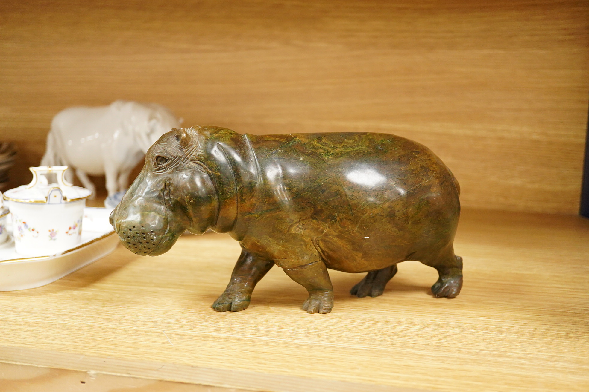 A carved serpentine study of a walking hippopotamus, incised initials to the underside 'E.S.', 24cm wide